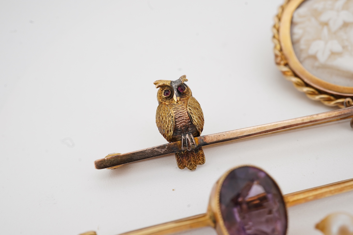 A 9ct owl bar brooch, with cabochon eyes, 50mm, a 1960's 9ct gold and amethyst set bar brooch, an 18ct and amethyst set bar brooch, a cameo brooch(a.f.) and a cultured pearl necklace with 9ct gold clasp.